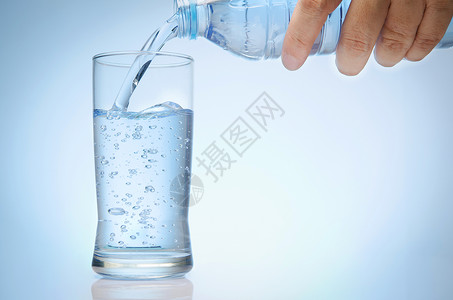 奎尔瓦瑟纯净的水从瓶子中倒入一杯背景