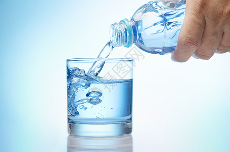 纯净的水从瓶子中倒入一杯高清图片