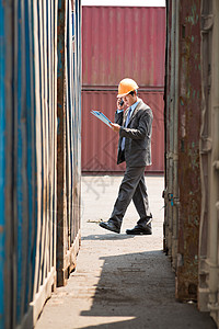 垂直图像一个忙碌的港口检查员通过电话打电话并配合他的计划图片