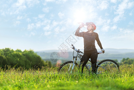 运动自行车女运动员在草地上喝酒图片