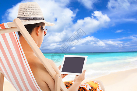 放松的人坐在沙滩椅上触摸平板电脑图片