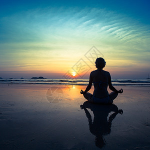 日落时坐在海边的瑜伽女人图片
