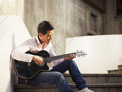 年轻人坐在台阶上弹吉他唱歌图片