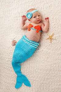 两周前刚出生的女婴穿着蓝色和橙色美人鱼装图片