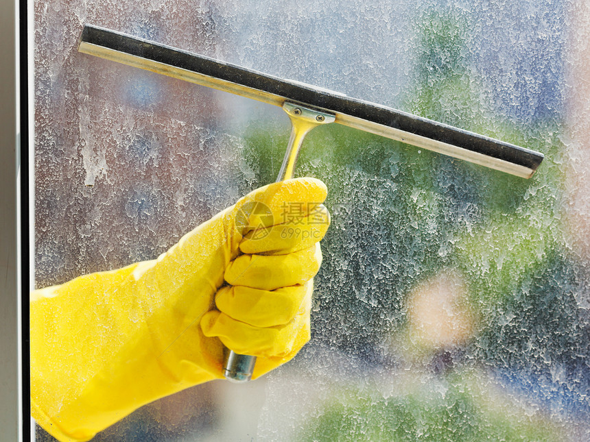在春日用黄色手套冲洗家用窗图片