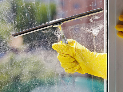 在春日用黄色手套洗家窗玻璃在春日图片