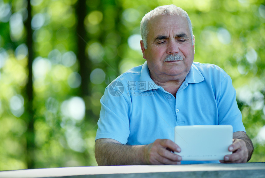 年长男子在用平板电脑阅读电子书或上网时图片