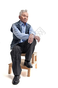 严肃的老人坐在白色背景的木楼梯上图片