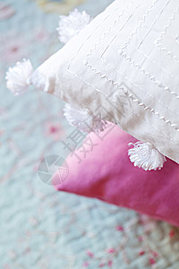 仔细观察一个刺绣的白色垫子和一个粉红色垫子放在温图片