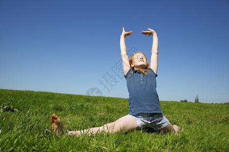 在绿色草地上劈叉的年轻女孩背景图片