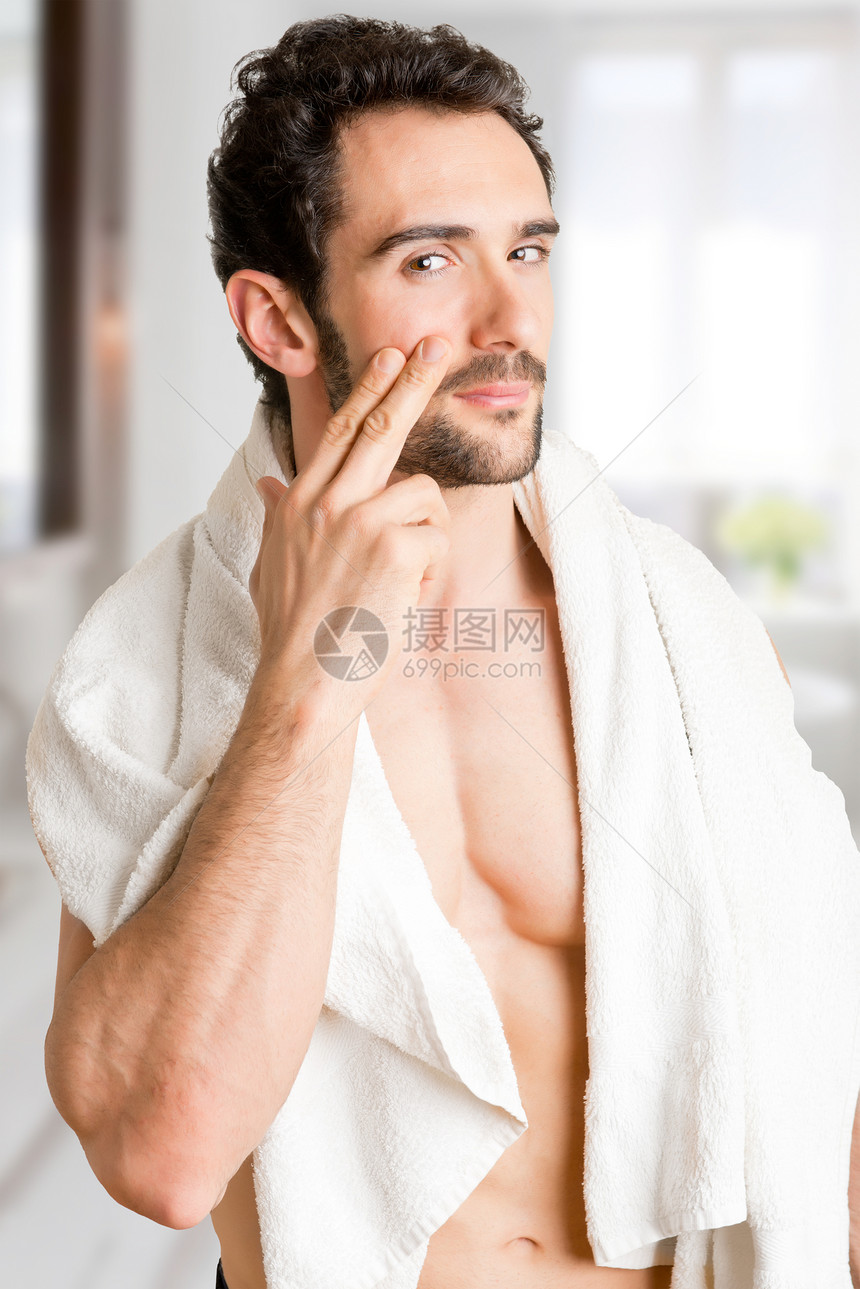 男在浴室里将保湿霜涂在脸上图片