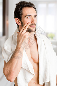 男在浴室里将保湿霜涂在脸上图片