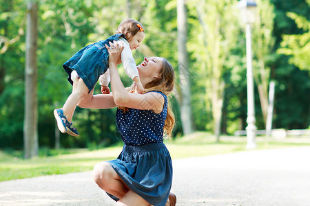 快乐的年轻母亲和可爱的幼儿女孩走过夏季公园一起在图片