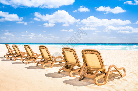 在热带空旷的海滩和绿松石海的日光浴躺椅图片
