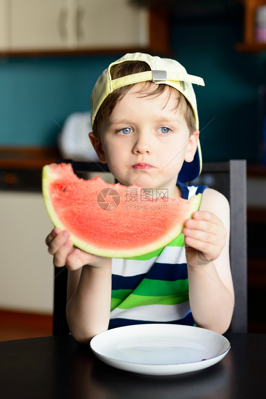 四岁快乐的男孩戴帽子吃西瓜图片
