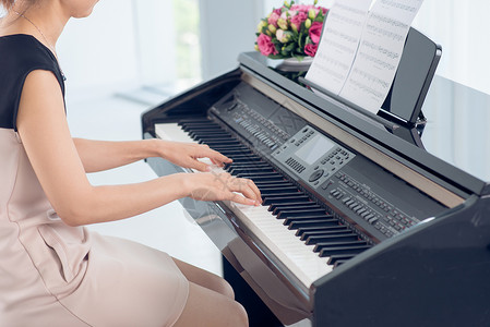 女在弹钢琴弹中身体和扣子时的侧边视图片