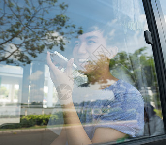 坐在巴士上用智能手机聊天的年轻人图片