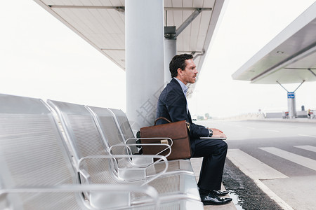 坐在机场公交车站椅子上坐着的商人图片