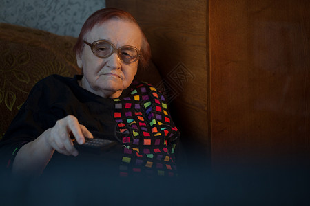 戴眼镜的老年妇女坐在沙发上背景图片