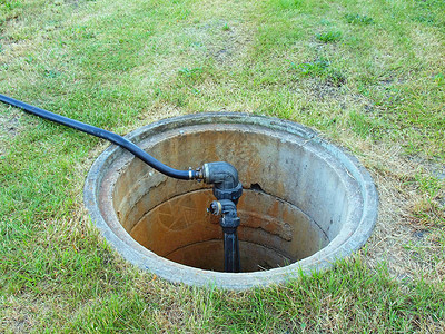 用灌溉系统的主水阀和塑料软管打开混凝土通道的盖子图片