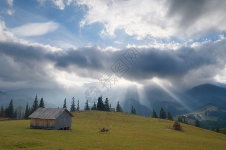 山上木林小屋风云中阳光照耀的图片