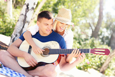 一张对年轻快乐的情侣坐在沙滩上背景图片