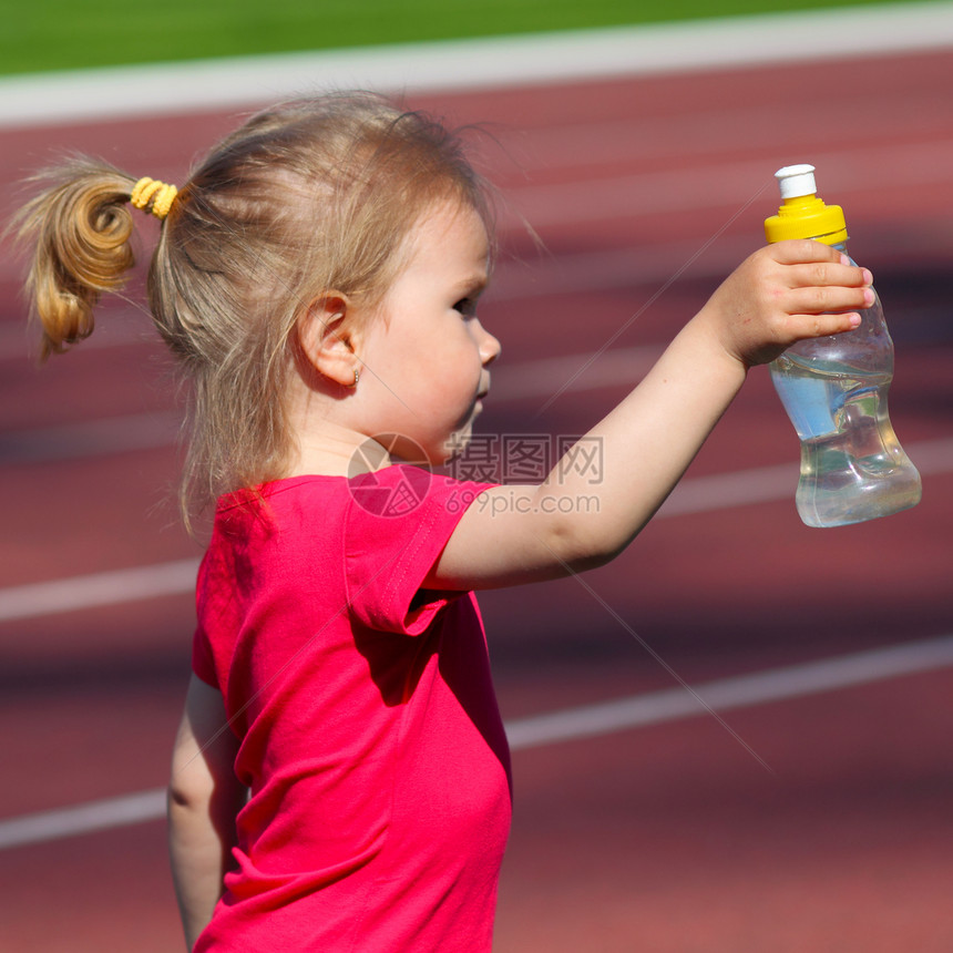 小女婴在体育场的瓶子里装水图片