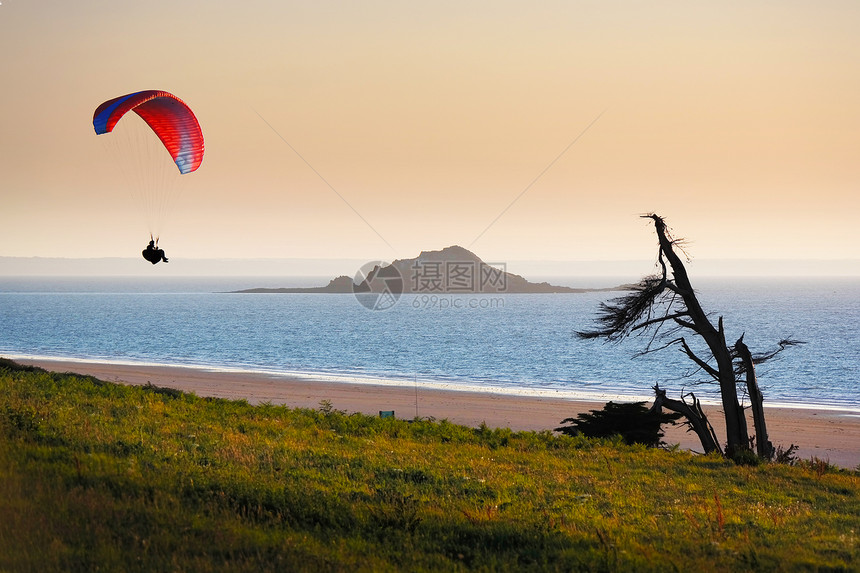 岸边日落时的孤独滑翔伞图片