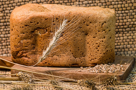 木板上的新鲜小麦面包和小麦对传图片