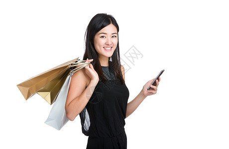 亚洲年轻女子拿着带购物袋的手机图片