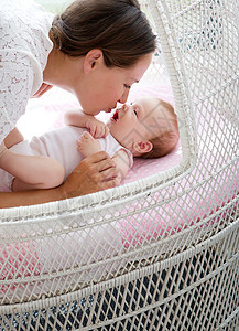 一位慈爱的母亲在床上亲吻婴图片