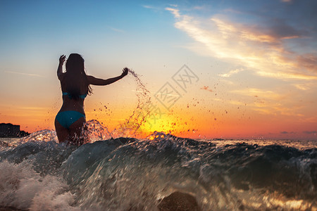 无忧虑的女子在沙滩上日落时跳舞假期活力图片