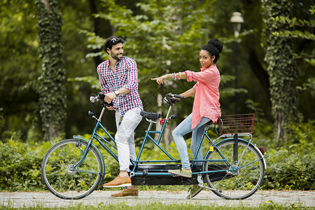 骑双人自行车的年轻夫妇图片