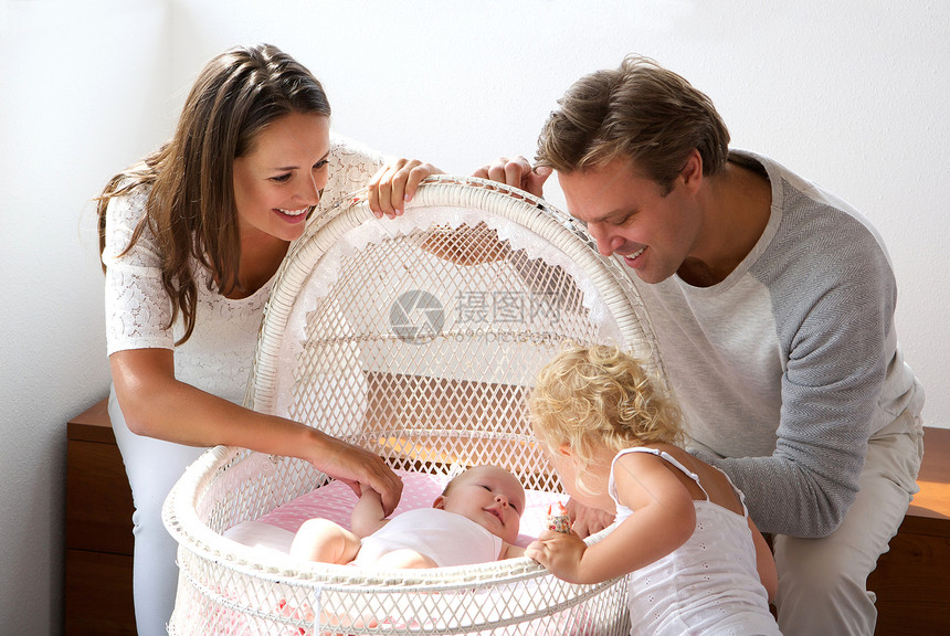 一个年轻家庭的肖像对在婴儿床的图片