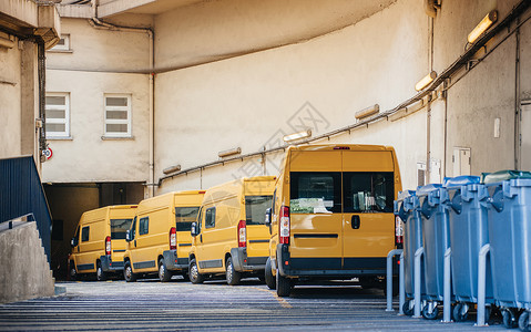 仓库配送物流厂入口前一排黄色送货和服务车高清图片