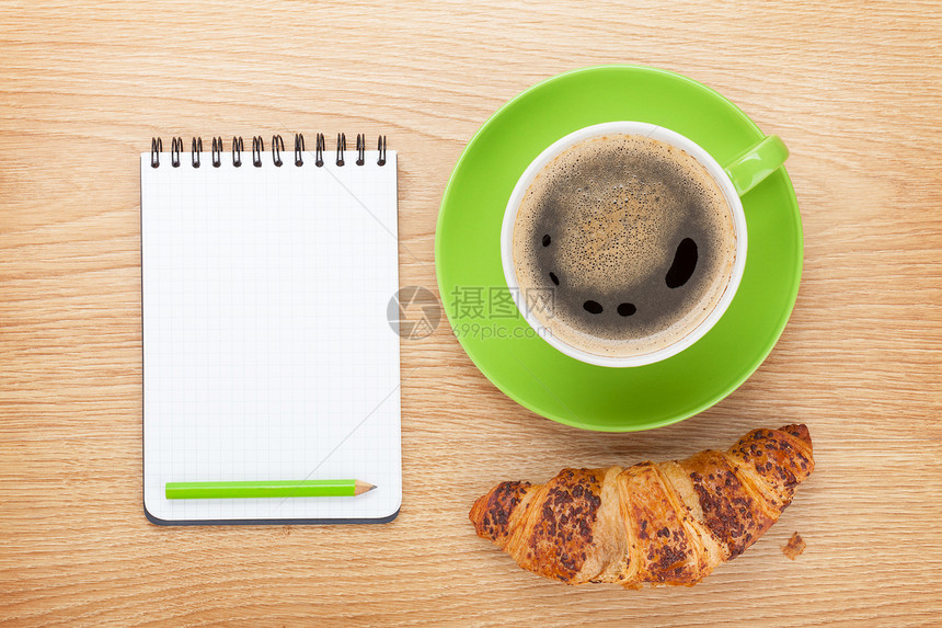 杯咖啡新鲜羊角面包和笔记板用于木制图片