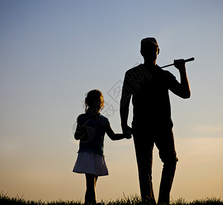 父亲和他的女儿在日落时打高尔夫球图片