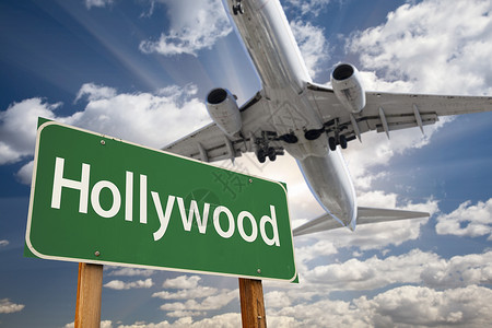 好莱坞绿色路标和空中飞机上面有图片