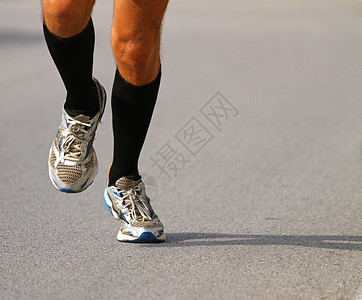 在马拉松公路铺面的马拉松期间骑着运动鞋图片