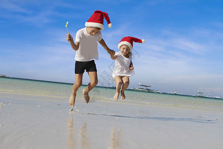 两个快乐的小孩戴着圣塔帽的孩子在自然热带背图片