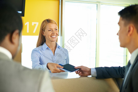 微笑的女将护照和机票归还机场商人的图片