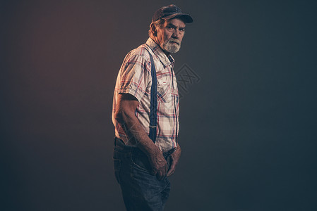 穿着蓝色帽子的灰发和胡子带牙套和牛仔裤的典型老年男子图片