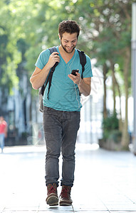 一个带着手机和袋子在城里行走的微笑着的男图片