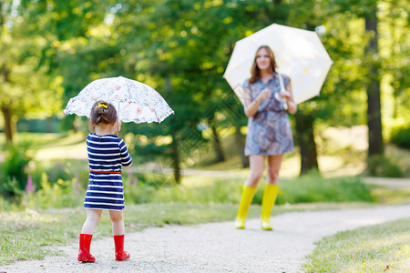 快乐的母亲和她的可爱小女孩穿着雨靴图片