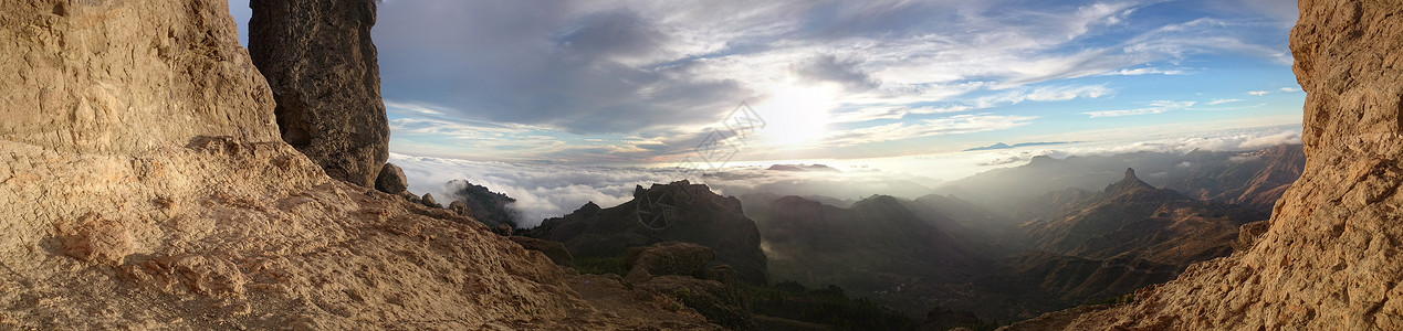 在遥远的山脉和山谷中太阳照在地平线上时透过岩石状山悬崖观图片