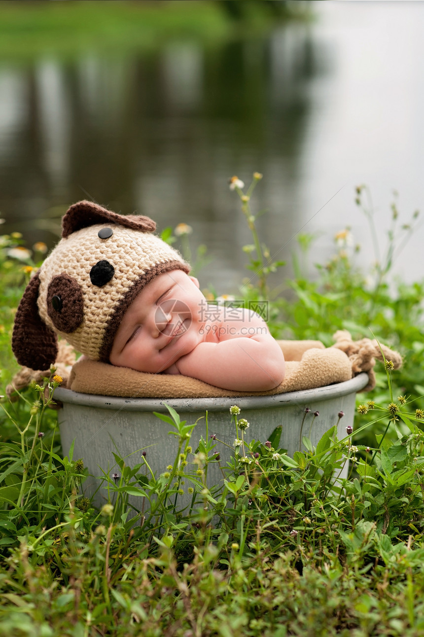 一个微笑的三个月大的男婴戴着钩针编织的小狗帽子图片