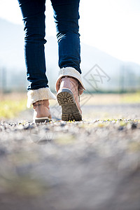 身穿牛仔裤和靴子的妇女脚踏在远离照相机图片