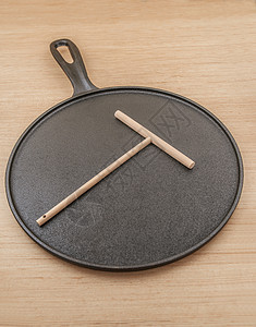 用于烘烤煎饼的铸铁平底锅和用于制作煎饼的木铲图片
