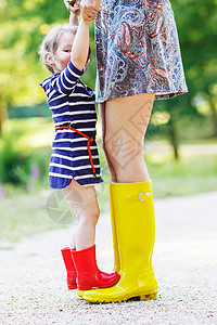 年轻母亲和小可爱的小女孩穿着橡胶靴子图片