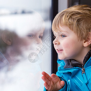 可爱的小孩在火车窗外看着车窗图片